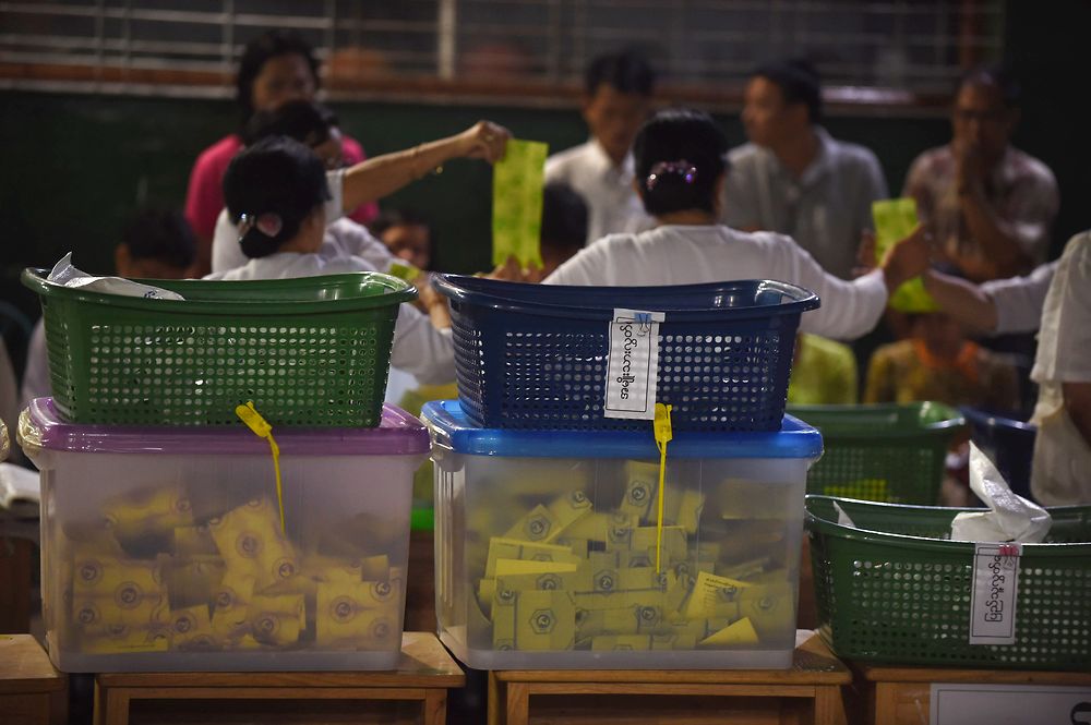 Poll officials conduct tabulation of votes before poll watchers of various political parties while ballots in ballot boxes (seen in foreground) are prepared for tabulation of votes in Yangon on November 8, 2015. Myanmar goes to the polls in an historic election that could thrust opposition leader Aung San Suu Kyi's pro-democracy party into power and pull the country away from the grip of the military. AFP PHOTO / ROMEO GACAD