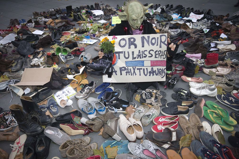 A man dressed as Yoda stands among shoes on the Place de la Republique which is covered in pairs of shoes on November 29, 2015 in downtown Paris, as part of a symbolic and peaceful rally called by the NGO Avaaz "Paris sets off for climate" within the UN conference on climate change COP21, as an attempt to get round the French authorities' ban on public gatherings. Paris has extended a ban on public gatherings introduced after the terror attacks in the French capital until November 30, the start of UN climate talks, where some 150 leaders will be tasked with reaching the first truly universal climate pact. Placard reads : "Black gold you shall leave. Peace you shall get". AFP PHOTO / JOEL SAGET