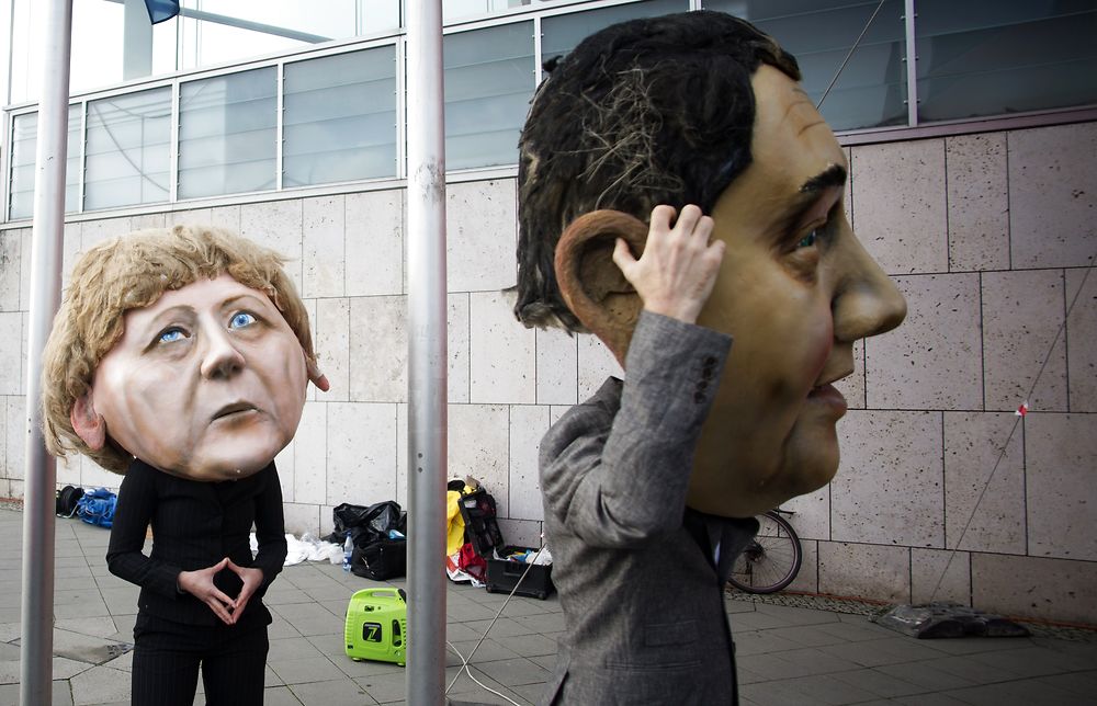 TOPSHOTS Activists of the action alliance campact wear masks featuring German Chancellor Angela Merkel (L) and the leader of the social democratic SPD party Sigmar Gabriel as they demonstrate for the introduction of nationwide referendums in front of the venue where members of the social democratic SPD party and members of the conservative CDU/CSU union met for coalition talks on November 13, 2013 in Berlin. AFP PHOTO / JOHANNES EISELE