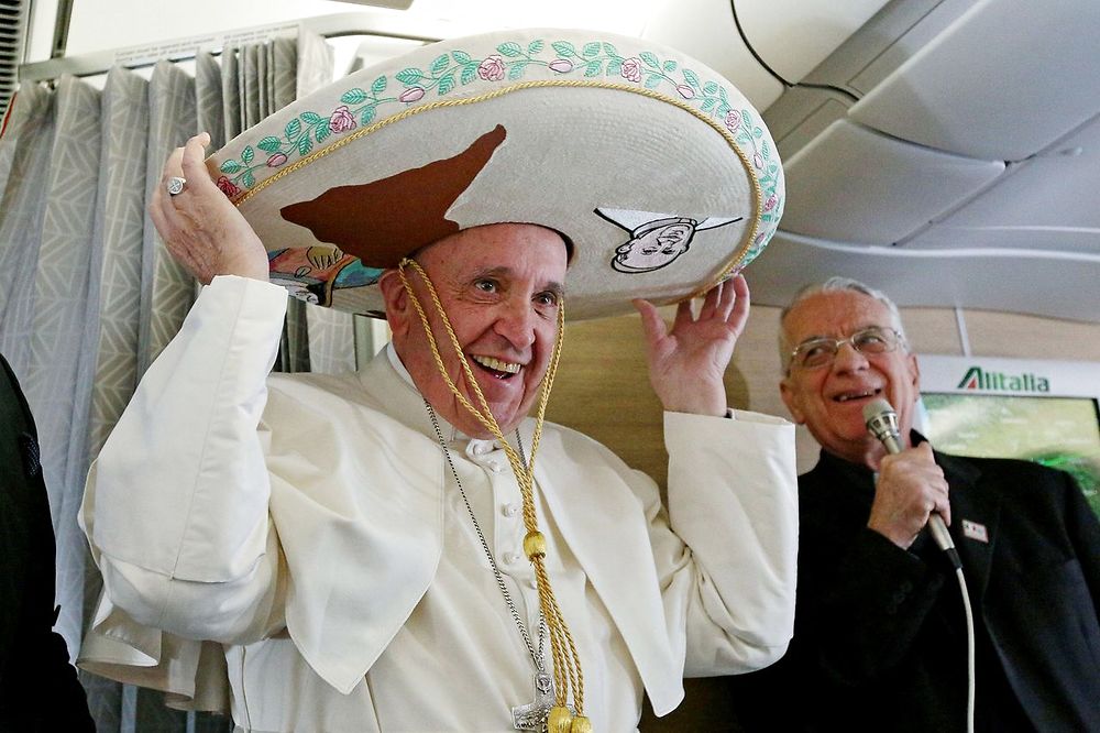 TOPSHOT - Pope Francis wears a traditional Mexican sombrero hat received as a gift by a Mexican journalist on February 12, 2016, aboard the plane to Havana. Pope Francis headed to Cuba on Friday looking to heal a 1, 000-year-old rift in Christianity before embarking on a tour of Mexico dominated by modern day problems of drug-related violence and migration. / AFP / POOL / ALESSANDRO DI MEO