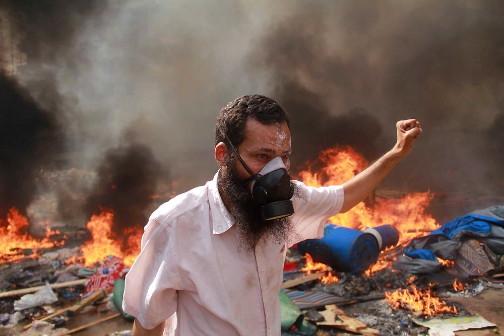 TOPSHOTS A supporter of the Muslim Brotherhood and Egypt's ousted president Mohamed Morsi gestures during clashes with police in Cairo on August 14, 2013, as security forces backed by bulldozers moved in on two huge pro-Morsi protest camps, launching a long-threatened crackdown that left dozens dead. The clearance operation began shortly after dawn when security forces surrounded the sprawling Rabaa al-Adawiya camp in east Cairo and a similar one at Al-Nahda square, in the centre of the capital. AFP PHOTO / MOSAAB EL-SHAMY